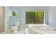 Bathroom with a soaking tub by a large window with a view of the backyard trees at 1213 Richmond Rd, Winter Park, FL 32789