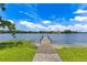 Picturesque view of a wooden dock leading to a serene lake, surrounded by lush greenery under a bright sky at 1213 Richmond Rd, Winter Park, FL 32789