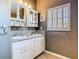 Bathroom featuring double sinks, granite countertops, white cabinetry, and a shuttered window at 1525 Oakwood Ct, Apopka, FL 32703