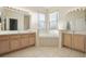 Bright bathroom featuring dual vanities, neutral tiling, and a garden tub with windows at 1601 Stoneywood Way, Apopka, FL 32712