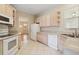 Cozy kitchen with light wood cabinets, white appliances and a view of the dining room at 1601 Stoneywood Way, Apopka, FL 32712