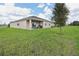 Rear exterior view of home features a covered patio, large yard and mature landscaping at 1670 Blue Lagoon Cir, Mascotte, FL 34753