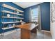 Office with blue walls, white shelving, a wood desk, and natural light from the window at 1670 Blue Lagoon Cir, Mascotte, FL 34753