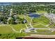 Expansive aerial view of community center showcasing green spaces and a pond, with some homes visible nearby at 1676 Blue Lagoon Cir, Mascotte, FL 34753