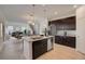 Bright, modern kitchen with stainless steel appliances, dark cabinets, and center island, opening to a living area at 1676 Blue Lagoon Cir, Mascotte, FL 34753