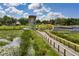 Picturesque park featuring a modern lookout tower, boardwalk over a pond, and lush greenery under a sunny sky at 1676 Blue Lagoon Cir, Mascotte, FL 34753