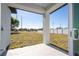 View of the backyard from a covered porch with a concrete floor and white support pillars at 1857 Manitoba Ct, Poinciana, FL 34759