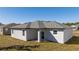Back exterior of the light-colored home with a gray roof and multiple windows at 1857 Manitoba Ct, Poinciana, FL 34759