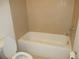 Bathroom with white tub, tile surround, and toilet at 1973 Portofino Meadows Blvd, Orlando, FL 32824