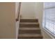 A carpeted staircase with a wood handrail leads to the upper level, illuminated by a window at 1973 Portofino Meadows Blvd, Orlando, FL 32824