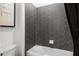 A close up on gray hexagon tiles above a white bathtub, with a partial view of the toilet at 2135 Weatherly Way, Orlando, FL 32820