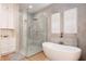 Bright bathroom featuring a walk-in shower, a freestanding tub, and white cabinets and drawers at 2161 Snow Rd, Orlando, FL 32814