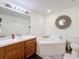 Bright bathroom featuring a wooden vanity, a soaking tub, and a large mirror at 2253 Lake Pointe Cir, Leesburg, FL 34748