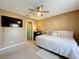 Bedroom with a ceiling fan, TV, and a view leading into the bathroom with blue shower curtain at 2253 Lake Pointe Cir, Leesburg, FL 34748