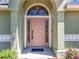 Close-up of the front door featuring an arched entry and sidelights, complemented by manicured landscaping at 2253 Lake Pointe Cir, Leesburg, FL 34748