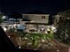 Aerial night view of a backyard featuring a patio, hot tub, outdoor kitchen, and palm trees with landscape lighting at 2403 Biscotto Cir, Davenport, FL 33897