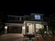 Exterior front view of a two-story home with a dark garage door and tastefully landscaped yard at night at 2403 Biscotto Cir, Davenport, FL 33897