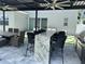 Outdoor living with kitchen, complete with a stainless grill, mini fridge, and barstool seating under a covered structure at 2403 Biscotto Cir, Davenport, FL 33897