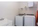 Bright laundry room featuring a modern washer, dryer, sink, and shelving at 288 Auburn Ave, Kissimmee, FL 34747