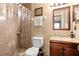 Bathroom featuring tiled shower, toilet, vanity, and a decorative mirror with light fixture above the sink at 288 Garland, Deltona, FL 32725