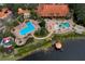 Aerial view of a community pool area with multiple pools, lounge chairs, and lush landscaping near a lake at 3018 Red Ginger Rd, Kissimmee, FL 34747