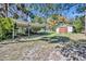 Backyard featuring shed, car port, green grass, and trees at 390 Lake Geneva Rd, Geneva, FL 32732