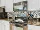 Close-up of a stove with a microwave, mosaic tile backsplash, and granite counters in the kitchen at 601 Orange Cosmos Blvd, Davenport, FL 33837