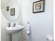 Clean powder room with pedestal sink, oval mirror, framed artwork and white walls at 601 Orange Cosmos Blvd, Davenport, FL 33837