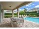 Outdoor patio with dining table and lounge chairs, overlooking the pool and landscaping at 7659 Wilmington Loop, Kissimmee, FL 34747