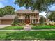 Stately two-story home featuring a brick walkway, manicured lawn, mature landscaping, and a grand entrance with twin balconies at 871 Cynthianna Cir, Altamonte Springs, FL 32701