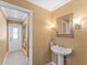 Stylish half-bathroom featuring a pedestal sink, decorative mirror and lighting, with neutral color palette at 871 Cynthianna Cir, Altamonte Springs, FL 32701