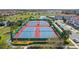 A birds eye view displays tennis courts bordered by lush trees near a pond and houses in a well-planned community at 10236 Beechwood Ln, Orlando, FL 32832