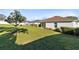 Well-manicured backyard with lush green grass, mature trees, and a partial view of the home's exterior at 1727 Garden View St, Mascotte, FL 34753