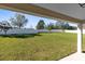 Spacious backyard featuring lush green grass and a white fence from the vantage point of the covered porch at 1727 Garden View St, Mascotte, FL 34753