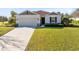 Inviting single-story home showcasing a lush green lawn, neutral exterior, and attached two car garage at 1727 Garden View St, Mascotte, FL 34753