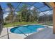 A sparkling blue pool within a screened enclosure, surrounded by lush greenery and clear skies at 176 Blue Jay Way, Davenport, FL 33896