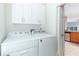 Laundry room with Whirlpool washer and dryer and overhead storage cabinets at 2166 Woodbridge Rd, Longwood, FL 32779