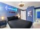 Themed bedroom with a comfortable black queen bed, ceiling fan, and blue walls at 2676 Emerald Island Blvd, Kissimmee, FL 34747