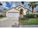 Charming single-story home featuring a manicured lawn, two-car garage, and inviting entryway at 2676 Emerald Island Blvd, Kissimmee, FL 34747