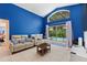 Bright living room with blue accent wall, tile flooring, and sliding glass doors to the pool area at 2676 Emerald Island Blvd, Kissimmee, FL 34747