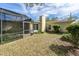 Backyard view with a screened in lanai, featuring mature trees and lush shrubs along the exterior wall at 3030 Kingfisher Dr, Orlando, FL 32806