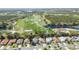 An aerial view highlights a residential area next to a golf course with mature trees and ponds at 3175 Arrowhead Ln, Kissimmee, FL 34746