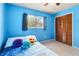 Bright bedroom with blue walls, a bed with decorative pillows and a louvred closet at 3455 Jujube Dr, Orlando, FL 32810