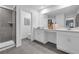 Bright bathroom with sleek, gray tiling, dual sink vanity, and modern shower with glass doors at 3489 Salvia Ct, Tavares, FL 32778