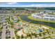 Community aerial view showcases large pool area, lazy river, walking bridge, and modern condo buildings near a picturesque lake at 4865 Clock Tower Dr, Kissimmee, FL 34746