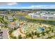 Community aerial view showcases large pool area, lazy river, walking bridge, and modern condo buildings near a picturesque lake at 4865 Clock Tower Dr, Kissimmee, FL 34746