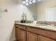 Bathroom featuring double sinks with granite countertop, wood cabinets, and decorative mirror and lighting at 4865 Clock Tower Dr, Kissimmee, FL 34746