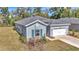 Side view of a blue single-Gathering home with a well-maintained lawn, shuttered windows, and a two-car garage at 7651 Sw 74Th Loop, Ocala, FL 34481