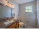 Clean bathroom featuring a wood vanity with a granite countertop, a large mirror, and a window for natural light at 7861 Copperfield Ct, Orlando, FL 32825