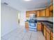 Efficient kitchen featuring wood cabinets, stainless steel appliances, and tile flooring, with a view to another room at 7861 Copperfield Ct, Orlando, FL 32825